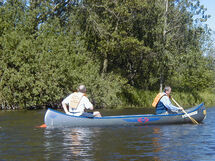 Two people paddling a canoe. Photo.