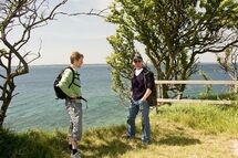 Two persons next to the water. Photo. 